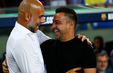 Barcelona's head coach Xavi Hernandez, right, greats Manchester City's head coach Pep Guardiola ahead of a charity friendly soccer match between Barcelona and Manchester City at the Camp Nou stadium in Barcelona, Spain, Wednesday, Aug. 24, 2022. (AP Photo/Joan Monfort)