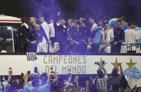 Coach Lionel Scaloni raises his fist from the bus taking the Argentine soccer team that won the World Cup to the training grounds where they will spend the night after landing at Ezeiza airport on the outskirts of Buenos Aires, Argentina, Tuesday, Dec. 20, 2022. (AP Photo/Matilde Campodonico)